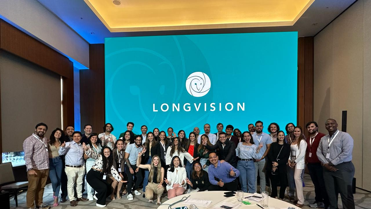 Several people posing for a photograph. Some in front, some behind. Everyone smiles. In the background, you can see a screen with our LongVision logo.